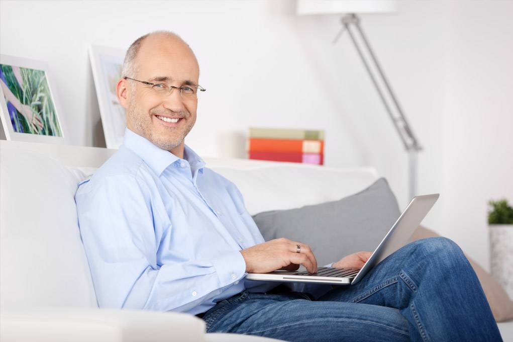 Man smiling while working on laptop